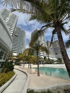 a resort swimming pool with palm trees and buildings at 1-BR Condo with 4 BEDS, DINING, Karaoke,NETFLIX,YTpremium,GAMES,WIFI,25TH fLoor - Sunrise & Sunset CITY&POOL view , wrap-around BALCONY in San Fernando +32 photos