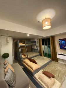 圣费尔南多1-BR Condo with 4 BEDS, DINING, Karaoke,NETFLIX,YTpremium,GAMES,WIFI,25TH fLoor - Sunrise & Sunset CITY&POOL view , wrap-around BALCONY的有两张双层床和一张沙发的房间
