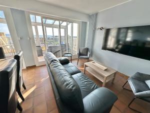 ein Wohnzimmer mit einem Ledersofa und einem TV in der Unterkunft Vue panoramique au 8ème étage avec 3 Terrasses & 1 Parking à Berck-Plage in Berck-sur-Mer