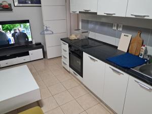 Il comprend une cuisine avec des placards blancs, un évier et une télévision. dans l'établissement Stan Lojkić, à Zagreb