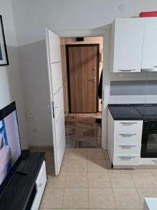 une cuisine avec des placards blancs et une porte marron dans l'établissement Stan Lojkić, à Zagreb