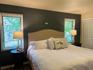 a bedroom with a white bed with two windows at Whitefish Home, Sleeps 7, Hot Tub, AC in Whitefish