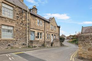 ein altes Steingebäude an der Straßenseite in der Unterkunft Daisy Cottage - North East Escapes in Corbridge