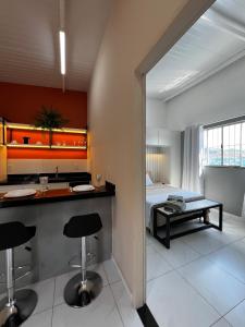 una cocina con barra y una cama en una habitación en Loft Sulfurosa - 800m do Parque das Águas, en São Lourenço