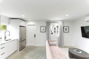 - une cuisine blanche avec un canapé rose dans l'établissement 1BD 1BA-Black&White ArtBNB Cottage-Antique Row WPB, à West Palm Beach 5 autres photos