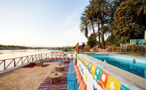 a resort with a pool and a beach with chairs at Fenti Nubian Resort in Aswan