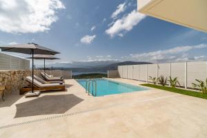 a swimming pool with an umbrella and a chair at Fantasea Villas, villa Lumi in Stérnai