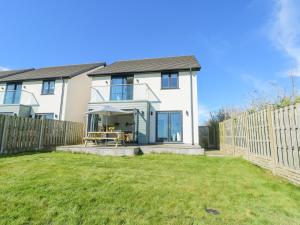a white house with a fence and a yard at 6 Gwel Yr Wyddfa in Rhosneigr