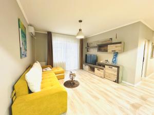 a living room with a yellow couch and a television at Apartament elegant - Cozy home residence in Piteşti +6 photos