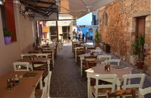 un restaurante con mesas y sillas y gente caminando por una calle en Enetiko Rooms en La Canea