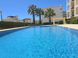 een groot blauw zwembad met palmbomen en gebouwen bij Mar a Vista in Albufeira +34 foto's