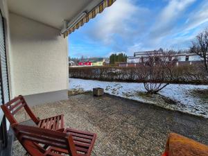 two chairs sitting on a patio with a snow covered yard at Cozy Farmhouse mit Terasse - 5min zum Waldweg in Bischofsgrün