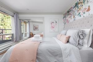 a bedroom with a large white bed with pink pillows at Boutique Beach Apartment in Vancouver