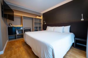 a bedroom with a large white bed and a television at Amérian Córdoba Park Hotel in Córdoba