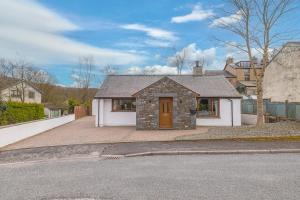 une maison en briques avec une porte marron dans une rue dans l'établissement Riverside Cottage 6 guests 4 adults max hot tub, à Backbarrow