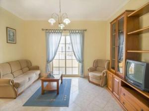 een woonkamer met een bank en een tv bij Casa Camarinha in Carvoeiro