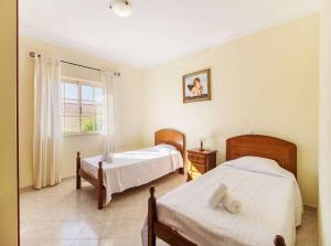 een slaapkamer met twee bedden en een raam bij Casa Camarinha in Carvoeiro +12 foto's