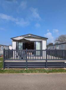 a house with a porch with an umbrella at PRESTIGIOUS BEAUTIFUL AND VERY SPACIOUS AMBLESIDE on AWARD WINNING SHOREFIELD COUNTRY PARK Entertainment Passes Included ST in Milford on Sea