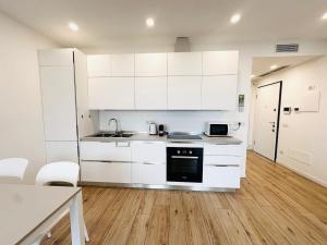 a kitchen with white cabinets and a wooden floor at The VIEW - Spacious modern apt in Como