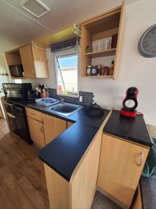 a kitchen with a black counter top in a room at Buxton's Holiday Home - 'Park Holiday's' complex - St Osyth - Clacton-on-Sea in Saint Osyth