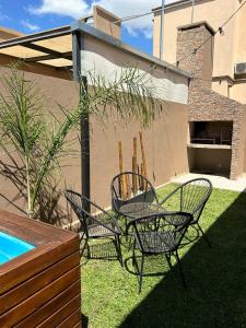 a patio with three chairs and a table in a yard at La Merced Areco Cabañas in San Antonio de Areco