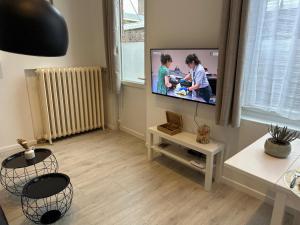 a living room with a flat screen tv on a wall at Appart Cosy avec Terrasse - Ideal Couple - Zen - LeRelaisdOdile41 in Valenciennes