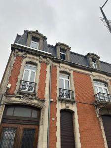 a red brick building with windows and a roof at Appart Cosy avec Terrasse - Ideal Couple - Zen - LeRelaisdOdile41 in Valenciennes