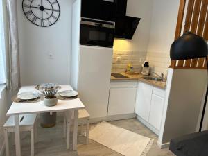 a kitchen with a small table and a clock on the wall at Appart Cosy avec Terrasse - Ideal Couple - Zen - LeRelaisdOdile41 in Valenciennes +10 photos
