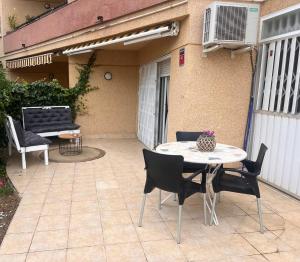 a patio with a table and chairs in front of a building at Acacias Playa in Hospitalet de l'Infant