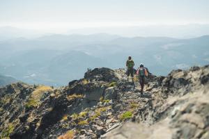 two people walking on the top of a mountain at Slalom Creek 2 Bedrooms in Rossland +3 photos