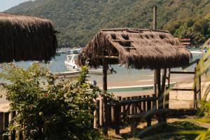 a hut with a bench and a boat in the water at MAMBEMBE hostel - Ilha Grande, Vila do Abraão in Abraão