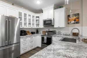a kitchen with white cabinets and a stainless steel refrigerator at Hip Gruene Condo, Walk to Gruene Hall, On River! in New Braunfels