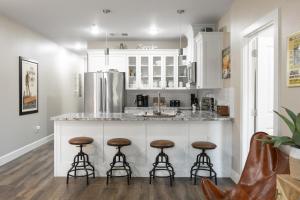 a kitchen with white cabinets and bar stools at Hip Gruene Condo, Walk to Gruene Hall, On River! in New Braunfels
