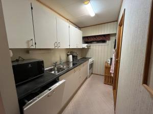 una piccola cucina con armadi bianchi e lavandino di Leilighet på Finnsnes, Senja a Senja