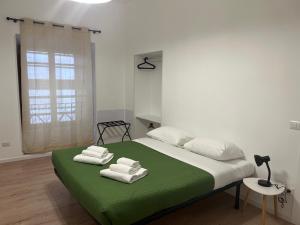 a bedroom with a green bed with towels on it at Ottaviano Lodge in Rome