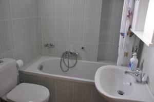 a bathroom with a toilet and a tub and a sink at neptune resort apartments in Kavos