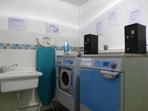 a bathroom with a washing machine and a sink at KOSY Appart'Hôtels - Le Cours Moreau in Mâcon