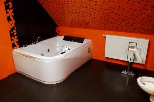 y baño con bañera y pared de color naranja. en Apartmánové byty so saunou a vírivkou, en Predajná 42 fotos más