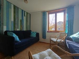 a living room with a blue couch and a window at Les jardins de Montaland in Sainte-Catherine-sur-Riverie
