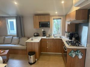 勒格劳德阿格德Résidence Camping Les Dunes的一间带木制橱柜和沙发的小厨房