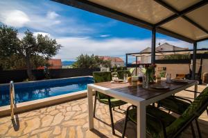 a table and chairs on a patio with a pool at Oleum - Family Home in Bol