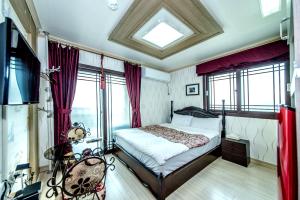 ein Schlafzimmer mit einem Bett in einem Zimmer mit Fenstern in der Unterkunft Jeju Hue Pension in Seogwipo