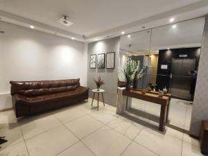 a living room with a brown leather couch and a table at Seaside Season Maceió in Maceió