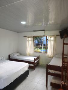 a bedroom with two beds and a window at Hotel Palma Paraíso in Melgar