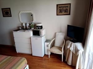 a room with a refrigerator and a television and a chair at Caminhada Guest Room in Mindelo