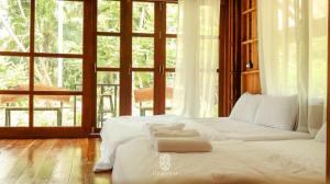 a white bed in a room with a large window at Mucoco Khanom in Ban Thong Tanot