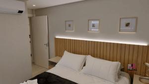 ベント・ゴンサルベスにあるApartamento Luxo em Bento Gonçalvesの木製のヘッドボードが付いた白いベッドのある寝室