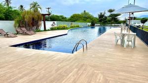 a swimming pool with chairs and a table and an umbrella at Studio 06 in Caruaru