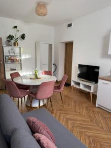 a living room with a table and chairs and a television at Dawna Mleczarnia Apartamenty SOSNOWY in Nowa Ruda