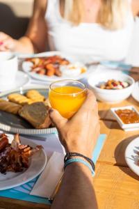 a person holding a glass of orange juice at a table with food at Rigas Boutique Hotel & Spa in Afitos